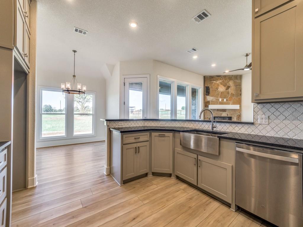 300 County Road 3141 Decatur, TX 76234 - Photo 8 of 25 a kitchen with granite countertop a stove a sink and white cabinets with wooden floor next to windows