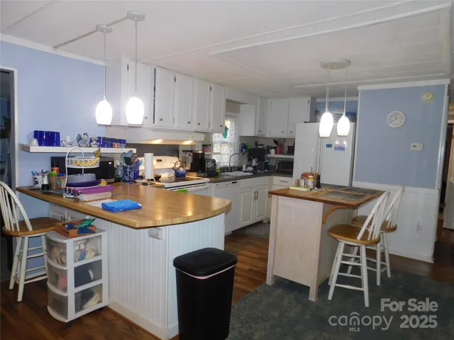 a kitchen with stainless steel appliances granite countertop a stove top oven a sink a dining table and chairs with wooden floor