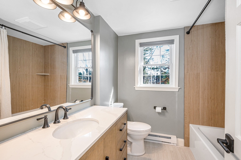 17 Autumn Street Windham, NH 03087 - Photo 28 of 42 a bathroom with a toilet a sink a mirror a window and vanity