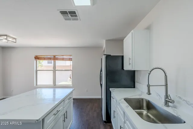 a kitchen with a sink a refrigerator and cabinets