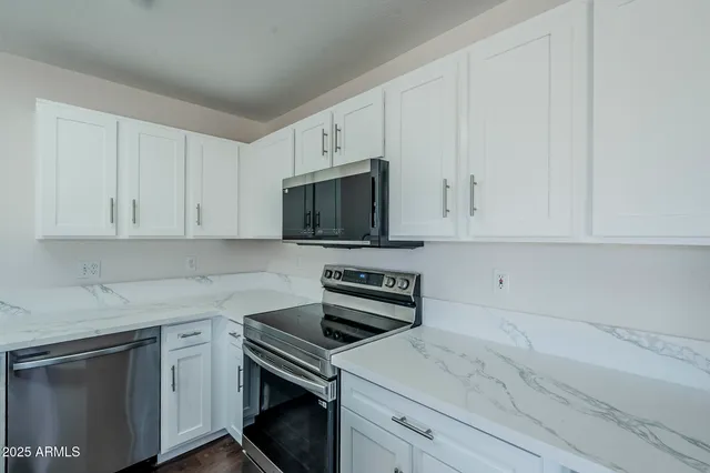 a kitchen with white cabinets and stainless steel appliances