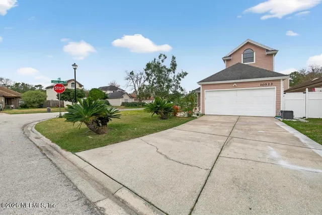 a backyard of a house with table and chairs plants and large tree