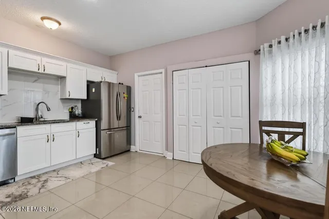 a kitchen with stainless steel appliances granite countertop a refrigerator sink and white cabinets