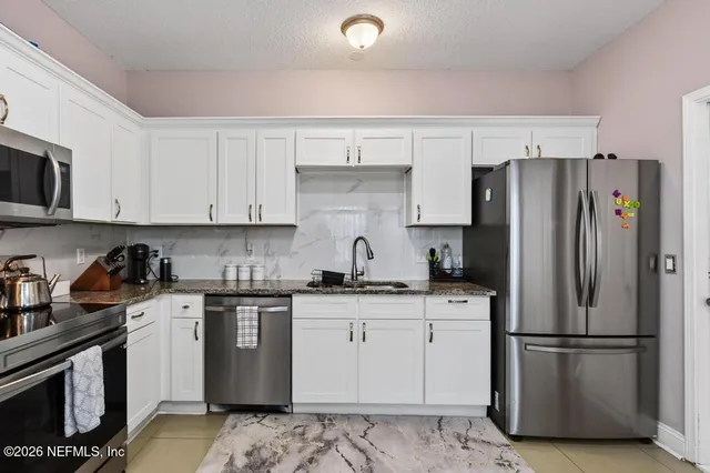 a kitchen with granite countertop white cabinets and a stove top oven