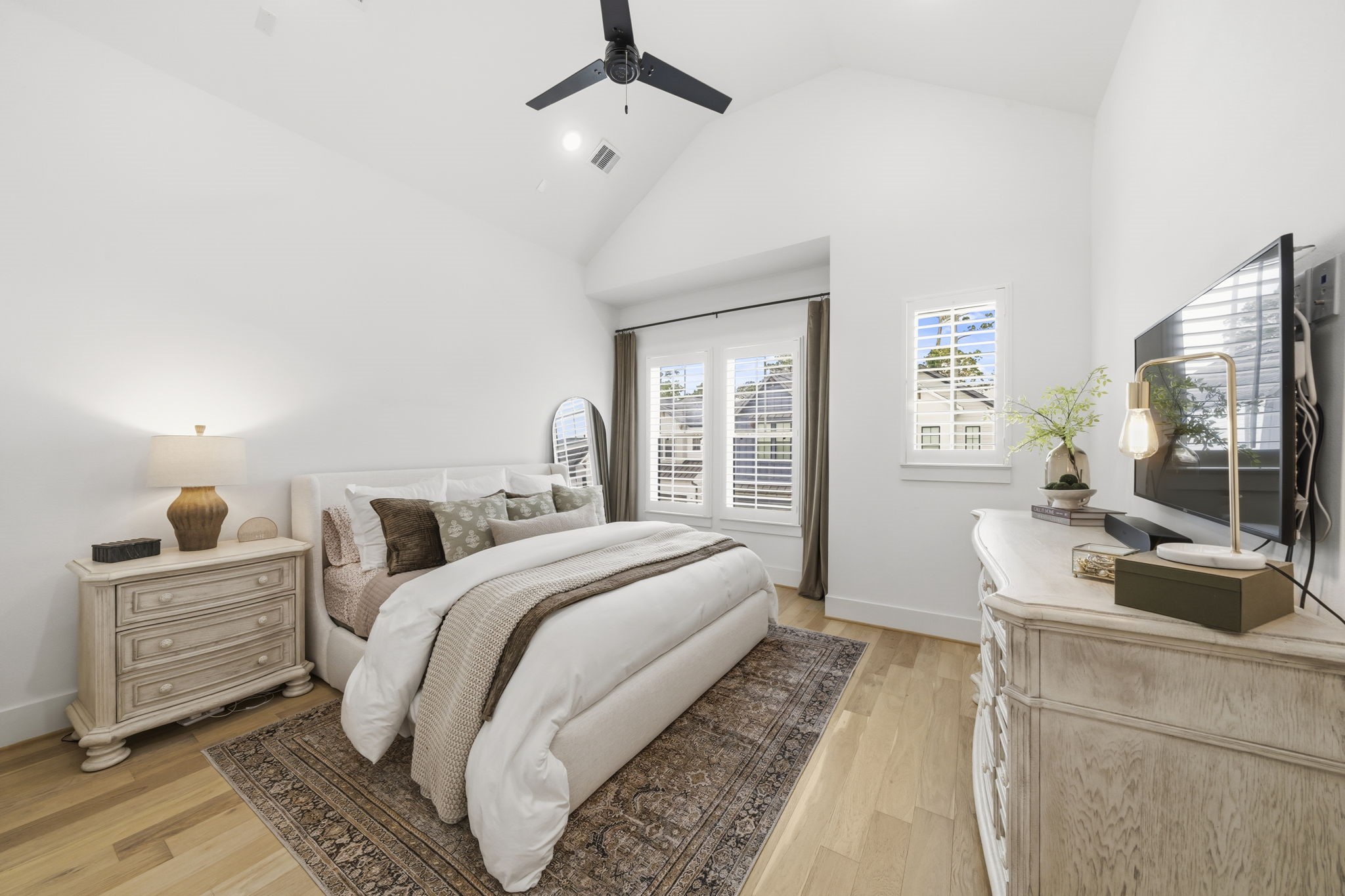 9018 Wellspring Drive Houston, TX 77080 - Photo 10 of 25 Escape to the impressive primary suite, defined by a dramatic vaulted ceiling and expansive windows outfitted with custom plantation shutters and blackout drapes for ultimate comfort.