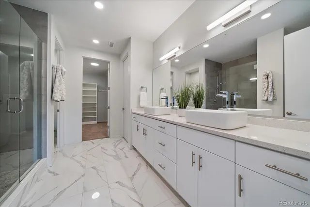 a bathroom with a double vanity sink a toilet a mirror and shower