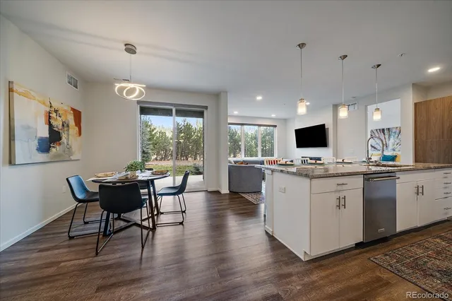 a kitchen with kitchen island granite countertop wooden floors and white cabinets
