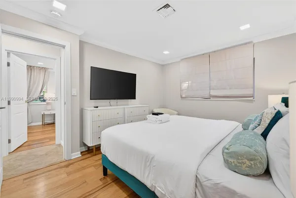 a bedroom with a bed and a flat tv screen on wall