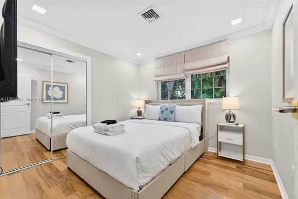 a bedroom with a bed a mirror and windows