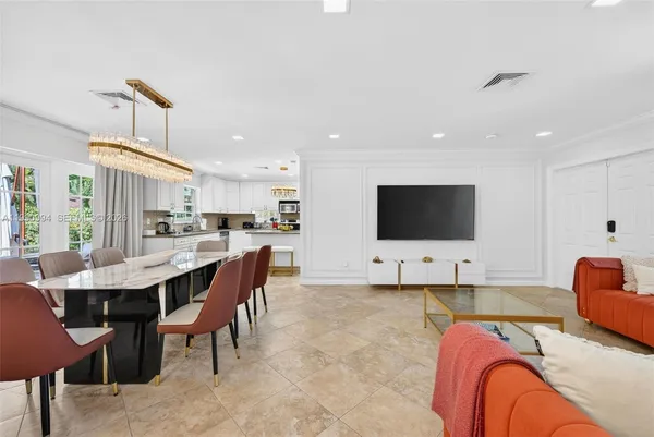 a living room with furniture a flat screen tv and kitchen view