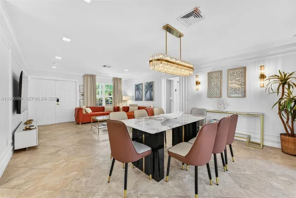 a view of a dining room and livingroom with furniture a rug a potted plant and a chandelier