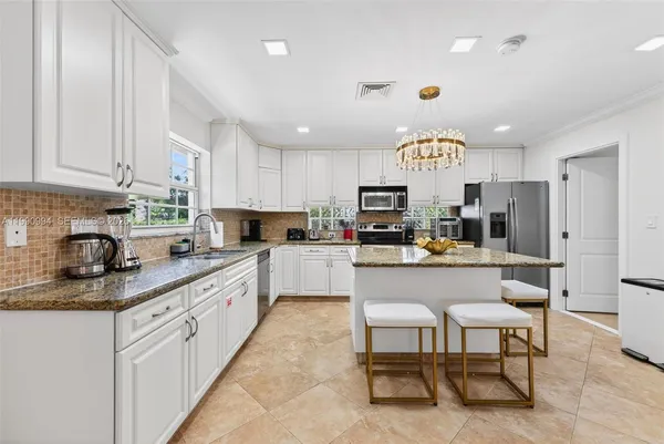 a kitchen with kitchen island granite countertop wooden cabinets and stainless steel appliances