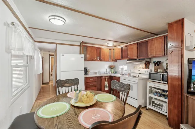 a kitchen with granite countertop lots of white furniture stainless steel appliances and a dining table