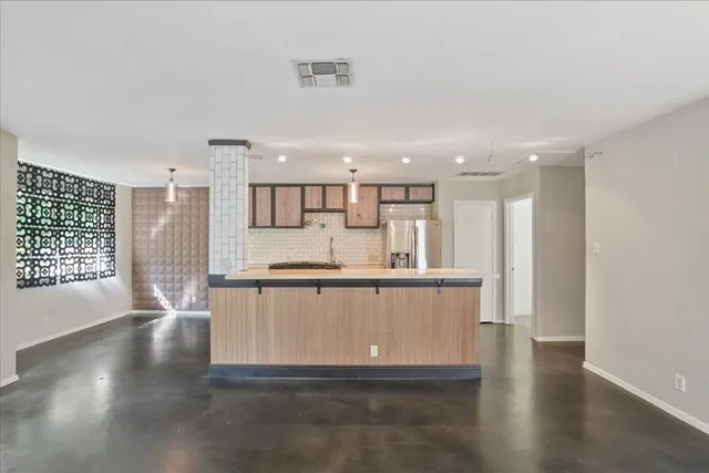 a large white kitchen with kitchen island a sink wooden floor and a refrigerator