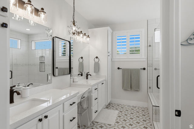 10676 Urban Rdg Cove South Jordan, UT 84095 - Photo 13 of 48 Bathroom featuring dual vanity with stone countertops, a standalone shower with a built-in bench, patterned floor tile, and a window with plantation shutters