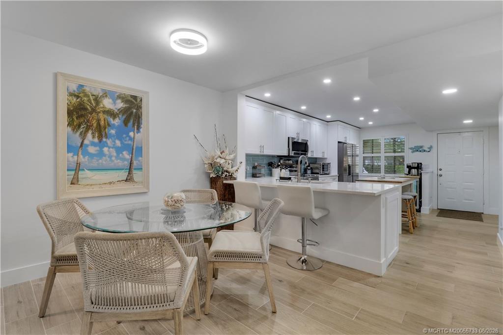 1001 Keystone Drive, Unit A Jupiter, FL 33458 - Photo 7 of 30 a kitchen with stainless steel appliances kitchen island granite countertop a table chairs and a refrigerator