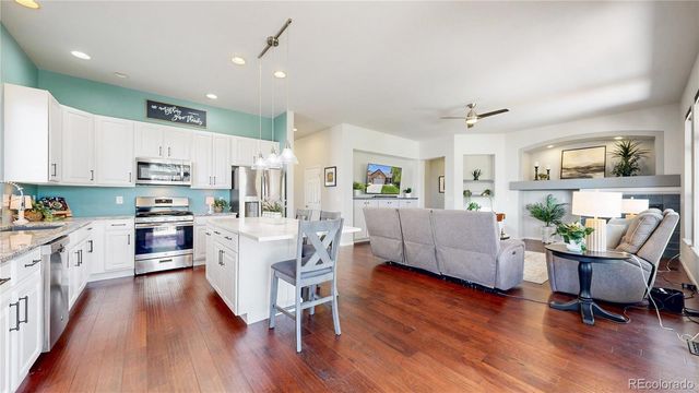 a living room with stainless steel appliances furniture and a wooden floor