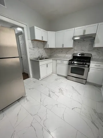 a kitchen with granite countertop a stove a sink and a refrigerator