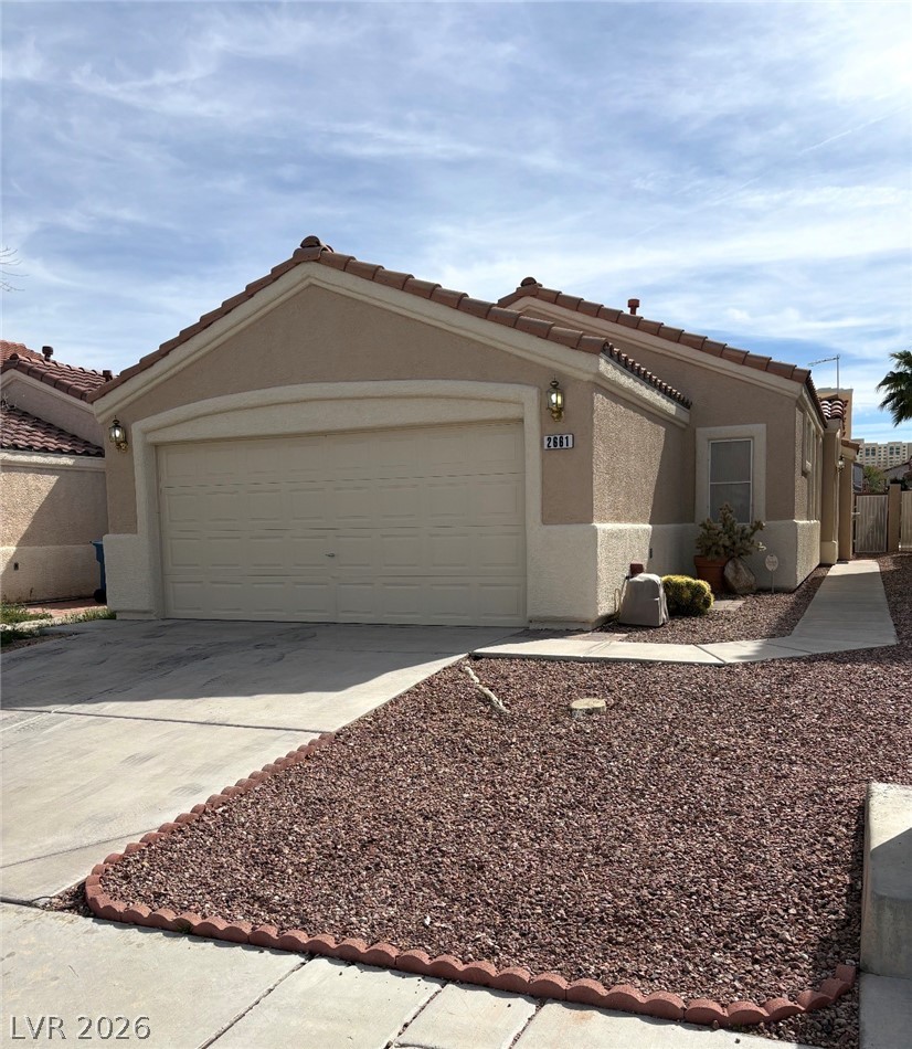 2661 Hillgrass Road Las Vegas, NV 89123 - Photo 2 of 27 View of front facade featuring concrete driveway, a garage, a tiled roof, and stucco siding