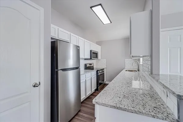 a kitchen with granite countertop a refrigerator and a sink