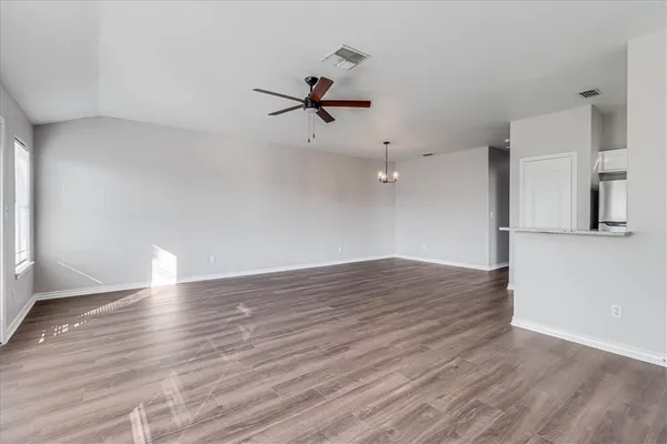 a view of empty room with wooden floor and fan