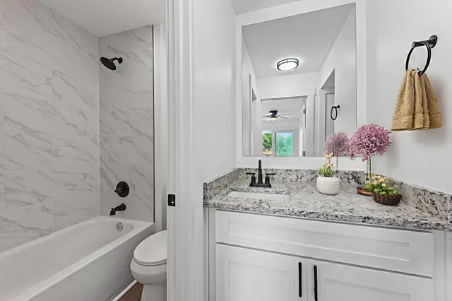 a bathroom with a granite countertop tub sink toilet and mirror