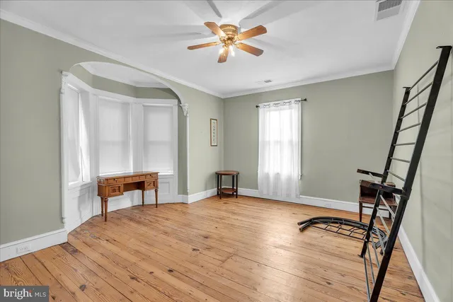 a view of an empty room with window and wooden floor