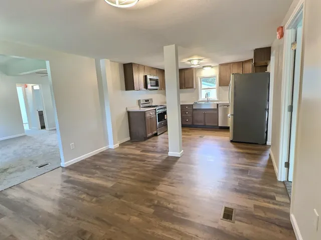 a view of a kitchen with refrigerator and wooden floor