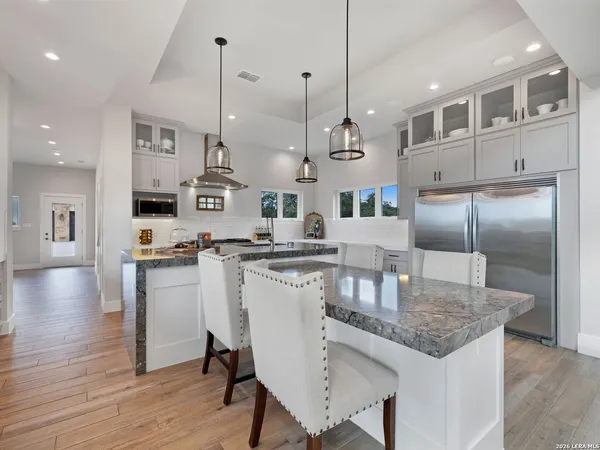 a kitchen with stainless steel appliances kitchen island granite countertop a table chairs sink and cabinets