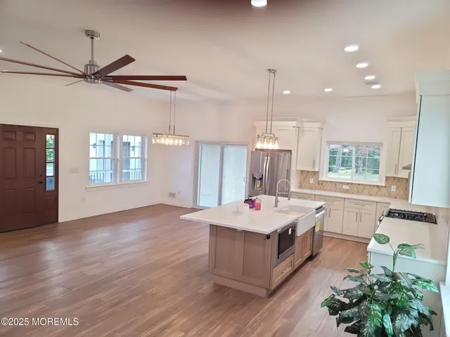 a large kitchen with kitchen island a stove a sink dishwasher and a dining table with wooden floor