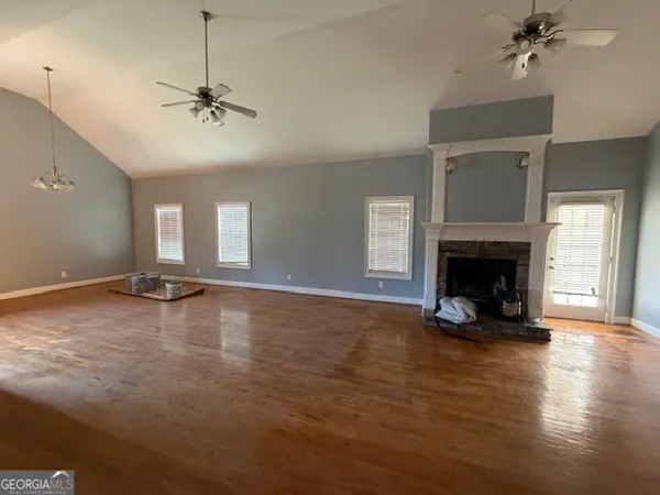 a view of a livingroom with a fireplace a ceiling fan and windows