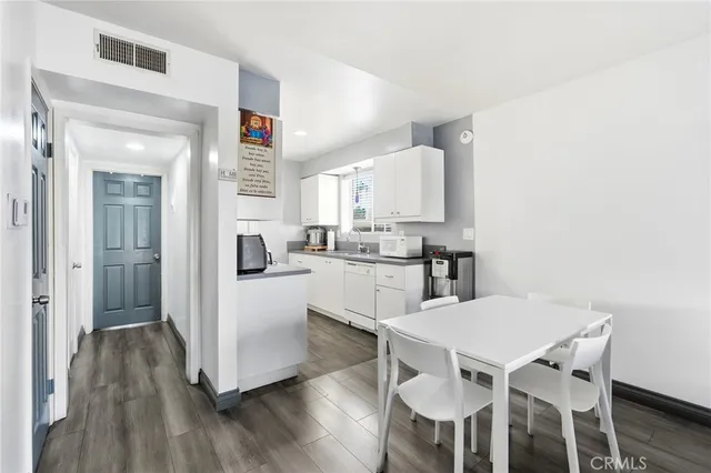 a kitchen with stainless steel appliances a dining table chairs and a refrigerator