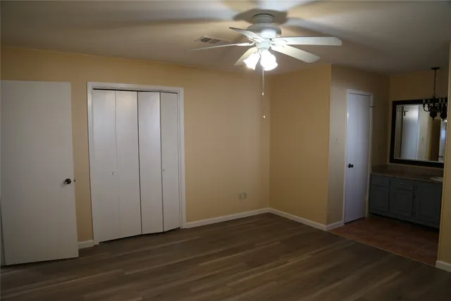 an empty room with wooden floor fan and windows