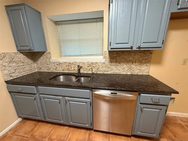 a kitchen with granite countertop a sink stove and cabinets