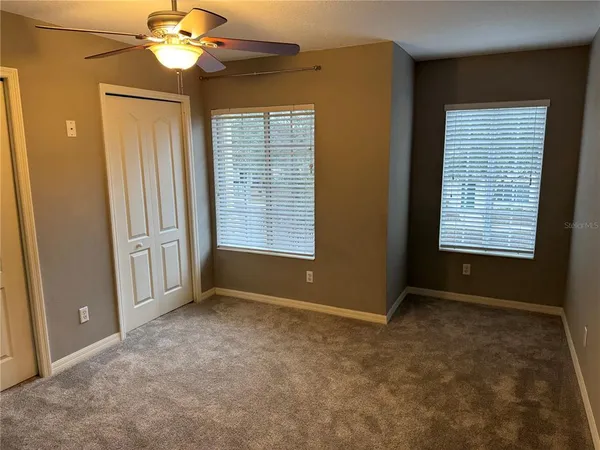 an empty room with windows and fan