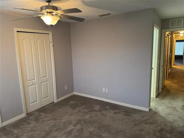 an empty room with a chandelier fan and a window