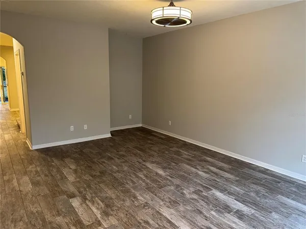 an empty room with a chandelier fan and windows