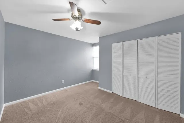 a view of an empty room with chandelier fan