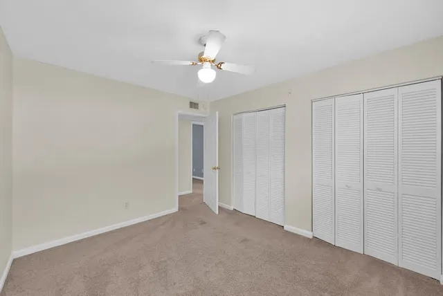 a view of an empty room and chandelier fan