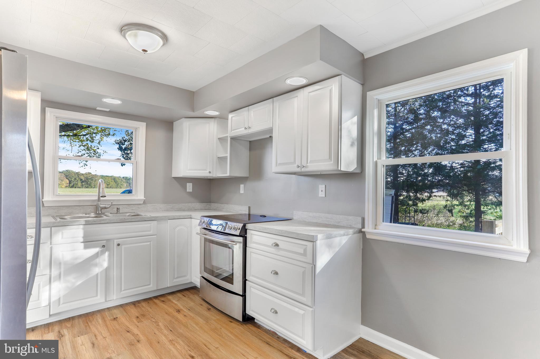 28154 Venton Road Princess Anne, MD 21853 - Photo 4 of 34 a kitchen with white cabinets and wooden floor
