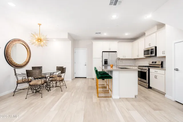 a kitchen with stainless steel appliances a stove a microwave a sink a refrigerator and white cabinets