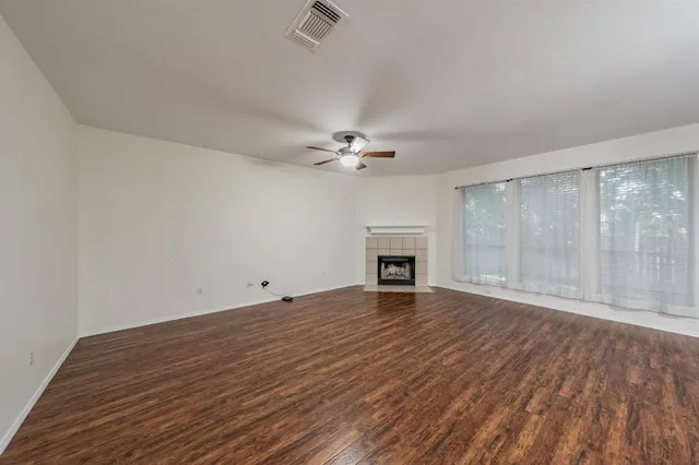 a view of an empty room with wooden floor and a fireplace