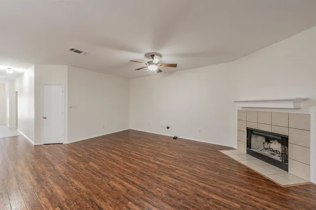 a view of an empty room with wooden floor and a fireplace