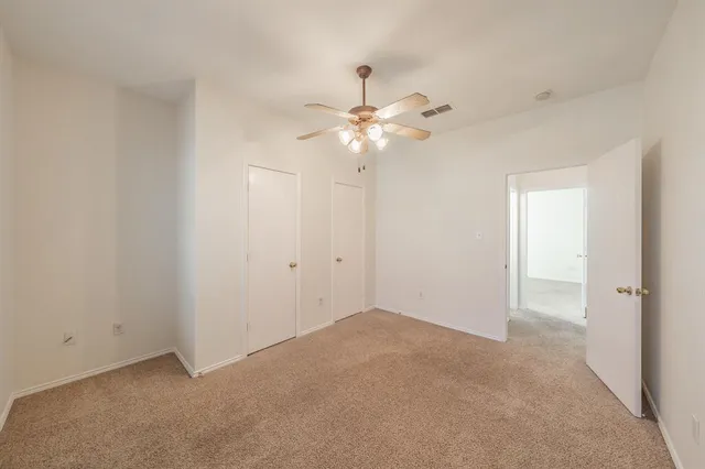 a view of an empty room with a chandelier fan
