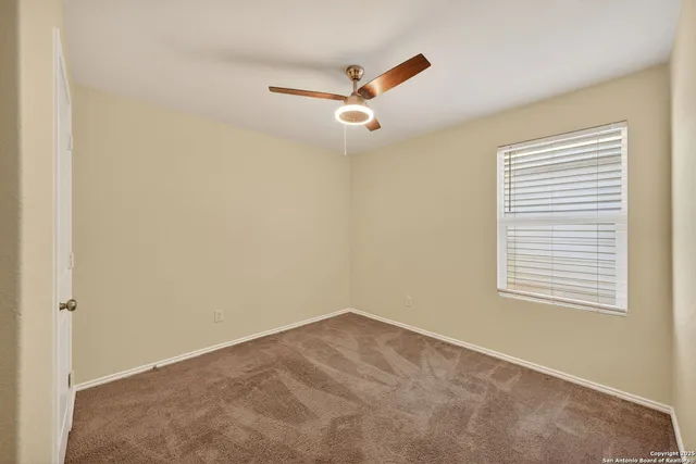 an empty room with a window and a ceiling fan