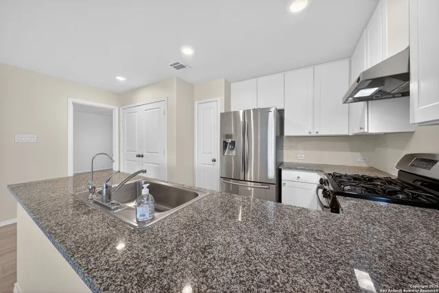 a kitchen with stainless steel appliances granite countertop a sink a stove a refrigerator a washer and dryer
