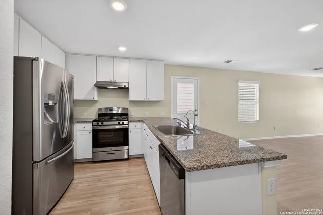 a kitchen with stainless steel appliances granite countertop a sink stove and refrigerator