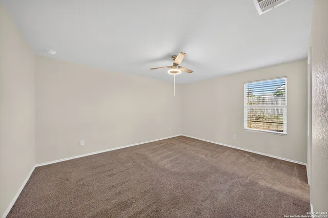 an empty room with windows and chandelier fan