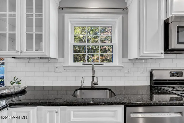 a kitchen with granite countertop a sink a stove and cabinets