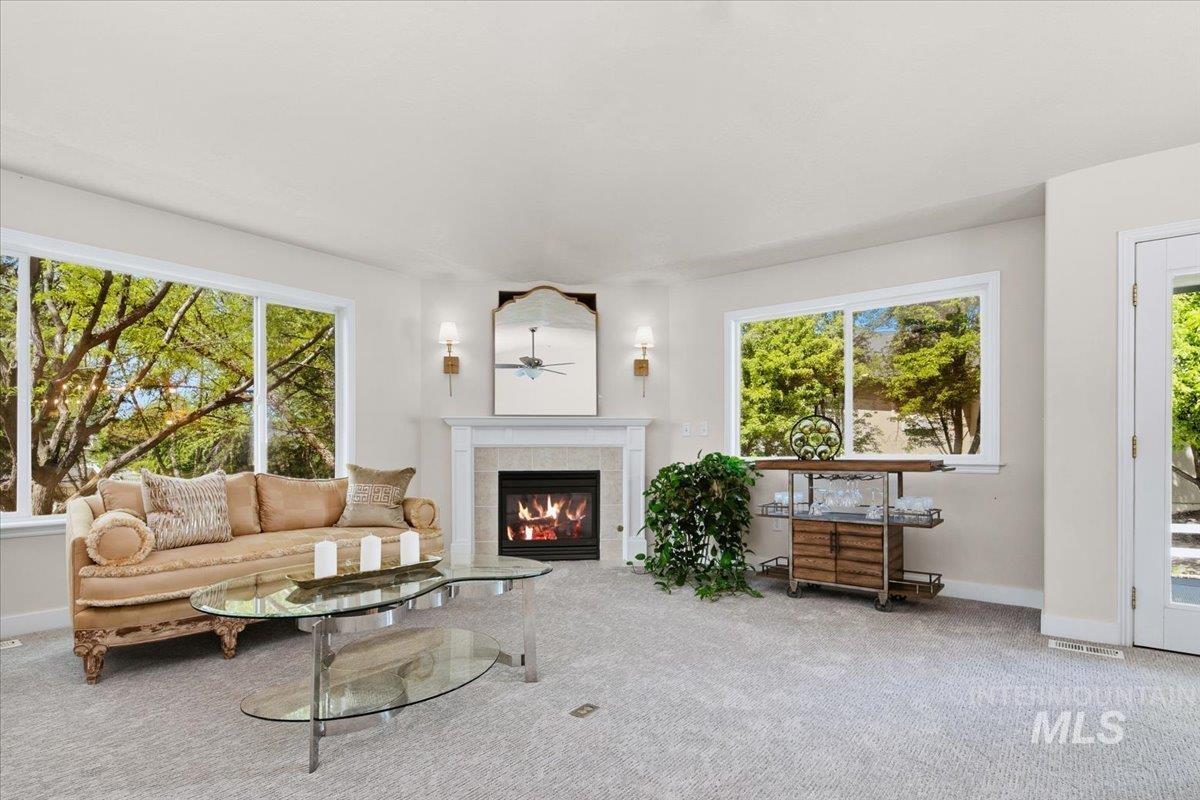 725 North Eagle Road Eagle, ID 83616 - Photo 13 of 45 Living area featuring a gas fireplace with a white mantel, dual wall sconces, and light-toned carpeting